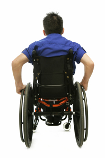 A man wearing a blue shirt rolls away in his wheelchair