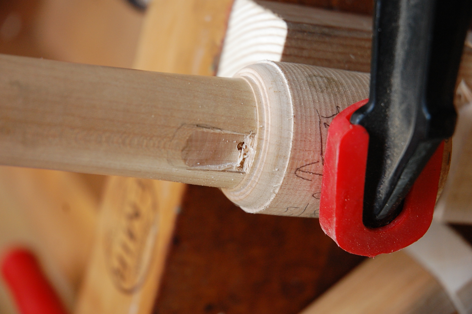 The head joint secured with a large, red clamp. Carving has just begun, and the labium is starting to take shape.